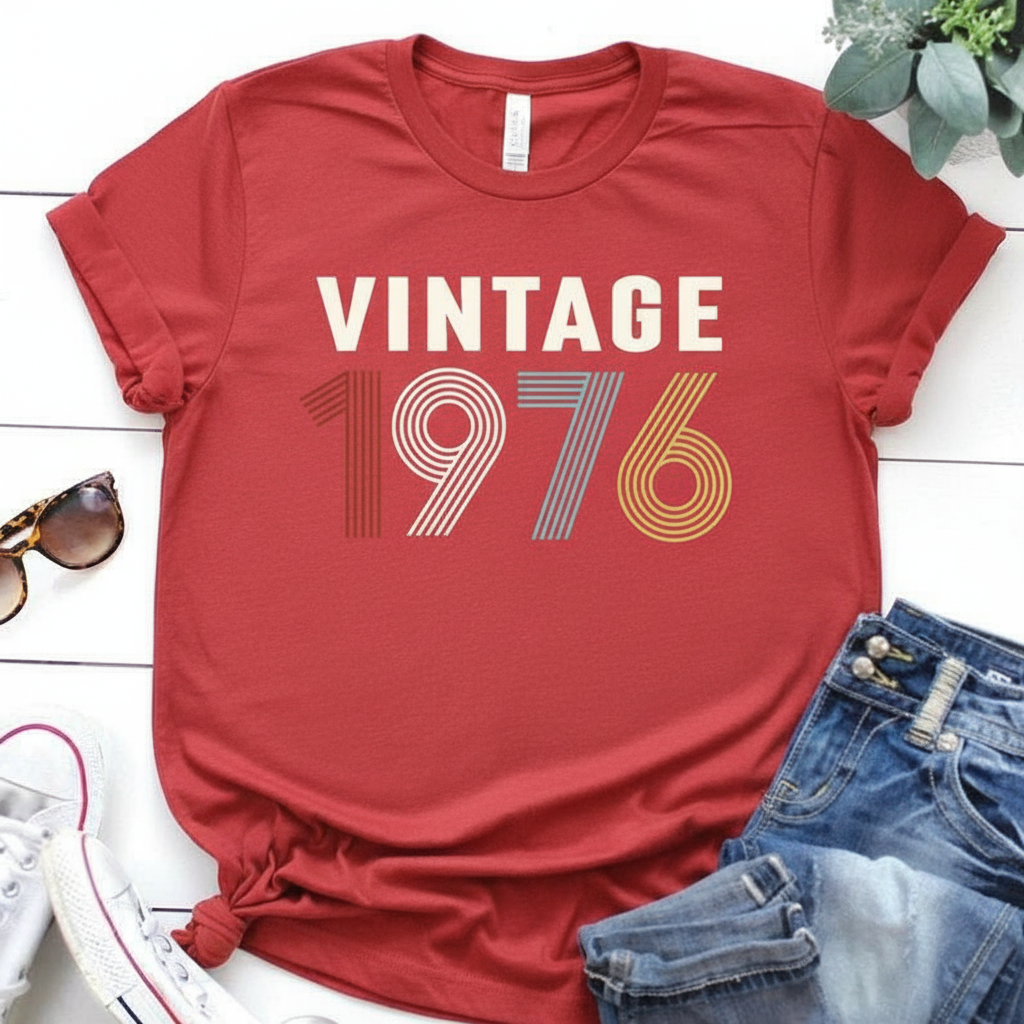 Red t-shirt with 'Vintage 1976' text on a white surface with accessories.