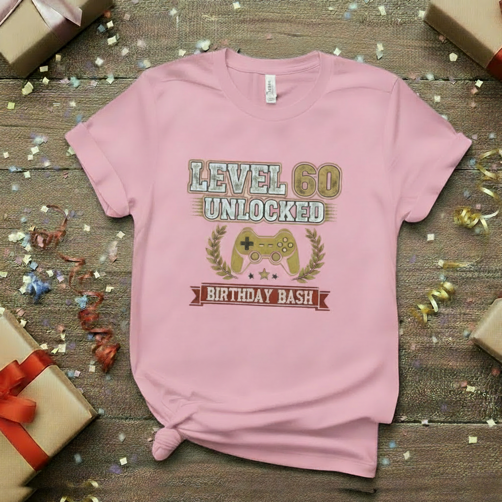 Pink t-shirt with 'Level 50 Unlocked Birthday Bash' design on a wooden surface with gifts and confetti.